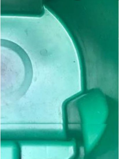 The inside of the same green wheeled bin after cleaning, the moulded plastic bare and rinsed clean